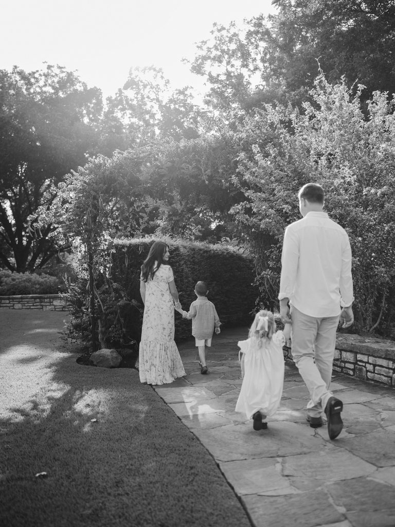 family of four walks underneath arches of flowers at the fort worth botanic garden