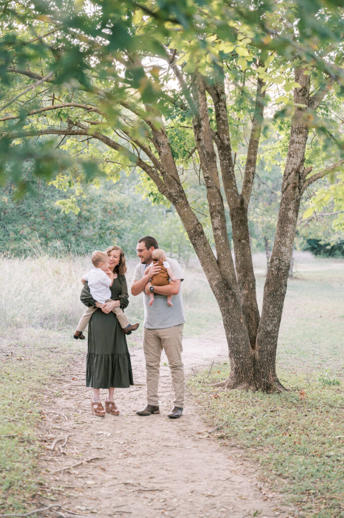 family walking under a tree on a path