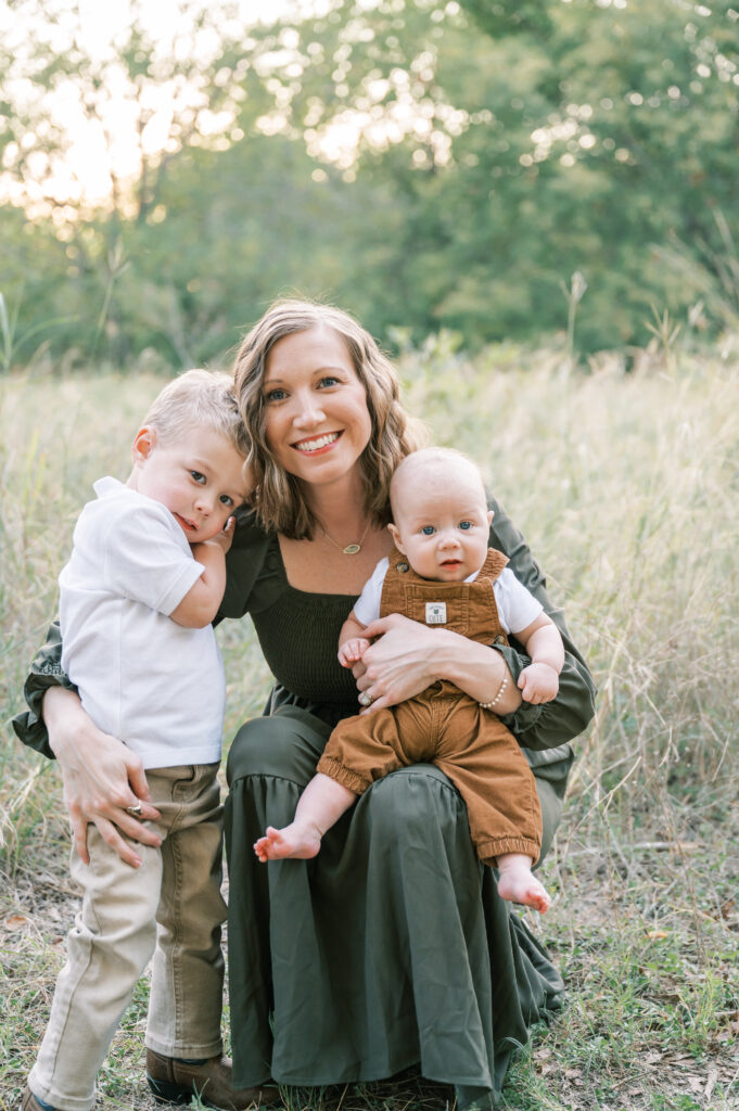 mom holds two sons and smiles for a photo