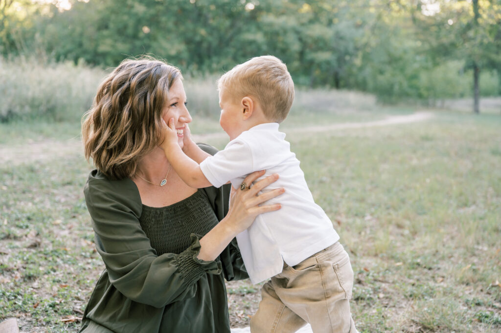 toddler son playfully touches mom's cheeks
