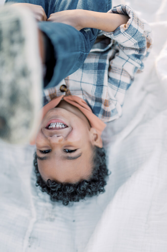 little boy rolls around on a blanket 