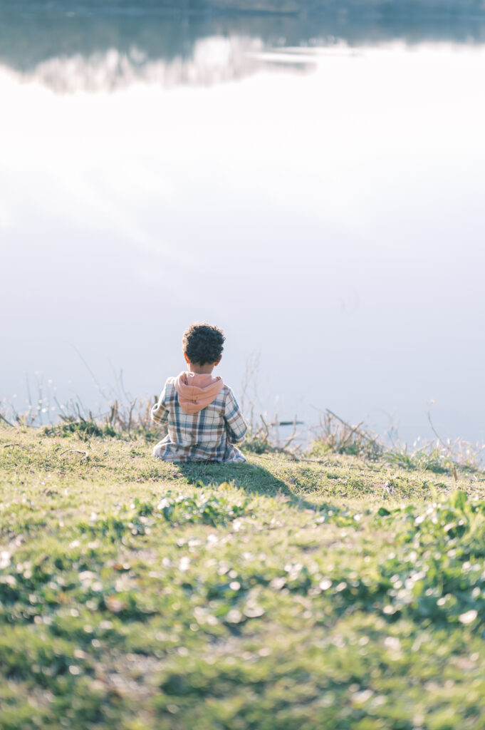 young boy sits on the edge of water looking out in Fort Worth 