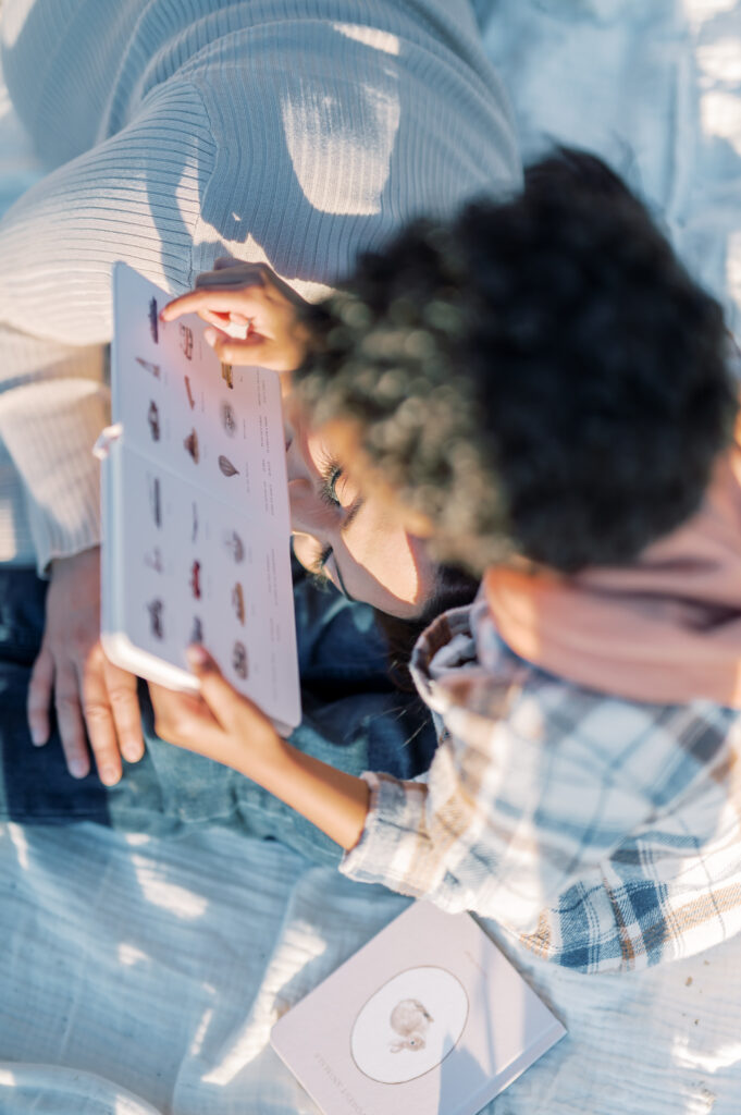 mom lays on son while he reads a picture book 
