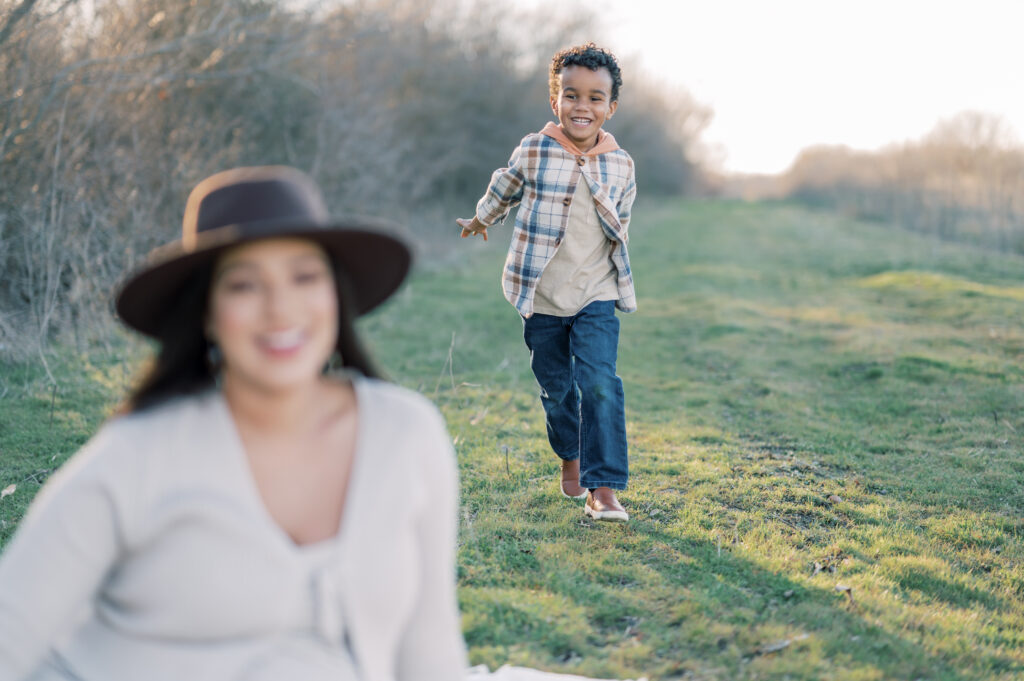 little boy runs behind mom with a big smile