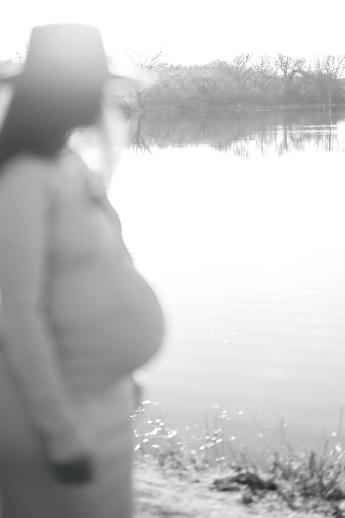 expecting mom looks out at the water during a maternity session in fort worth 
