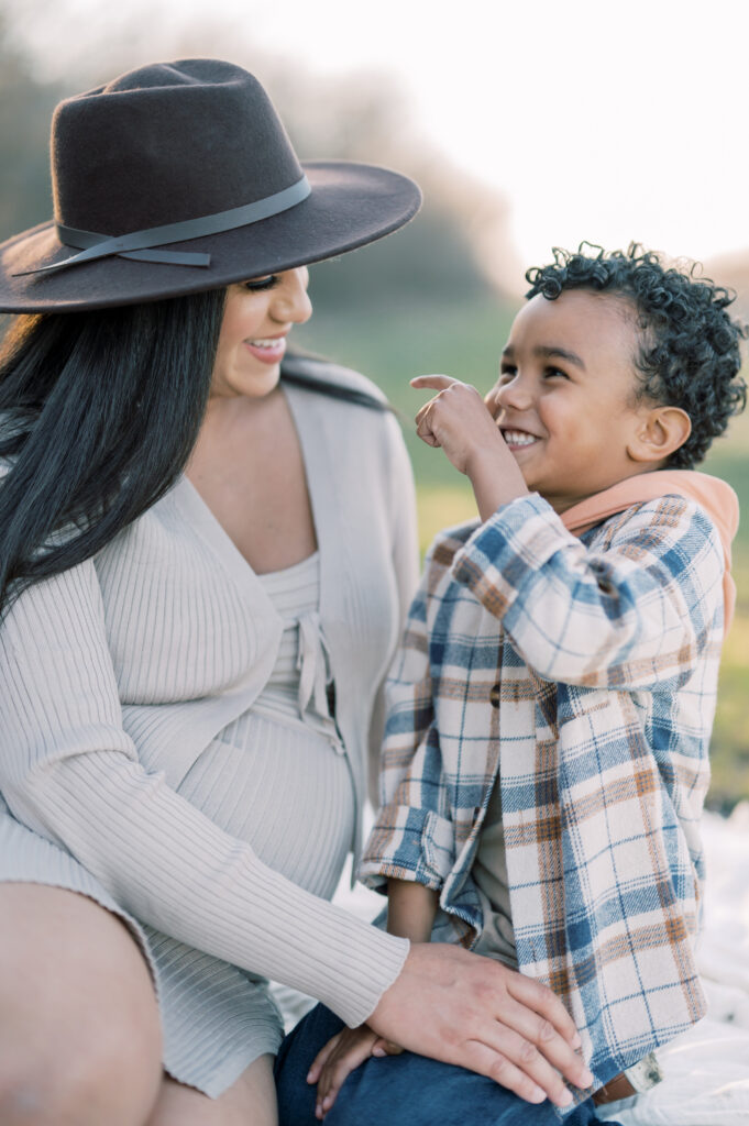 little boy points at pregnant mom with big smiles