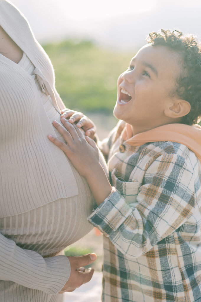 little boy smiles up at pregnant mom 