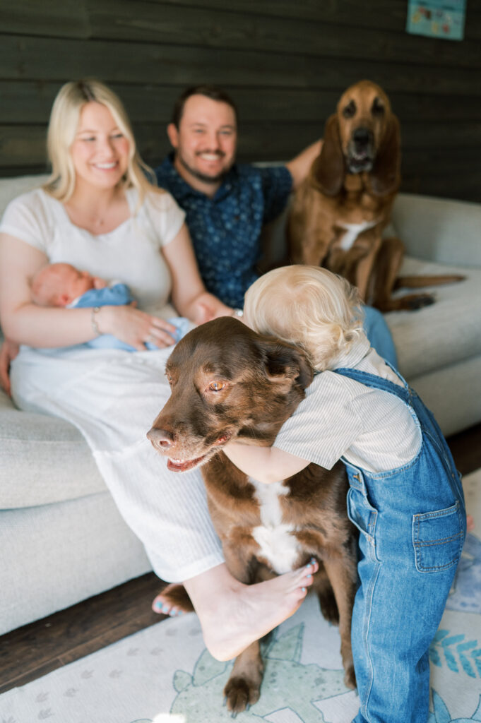 toddler hugs dog while family gathers on the couch