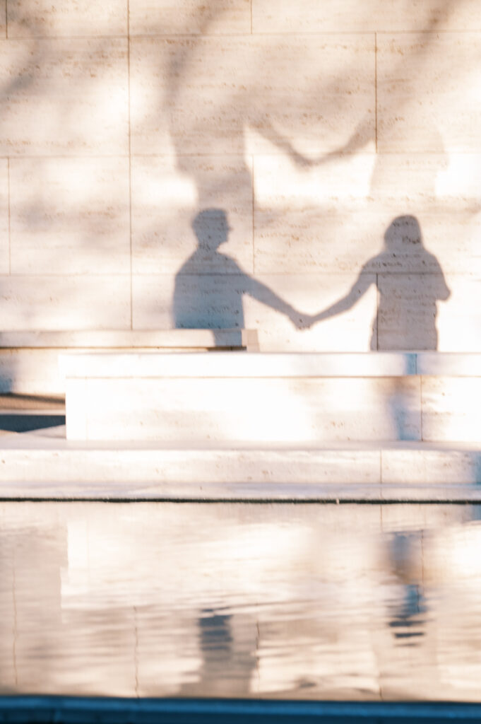 shadow of a couple holding hands including a water reflection at the kimbell art museum