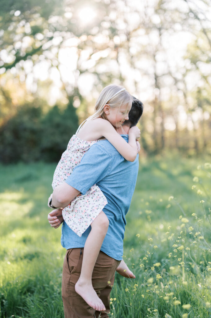 dad hugs daughter in a wildflower field in fort worth