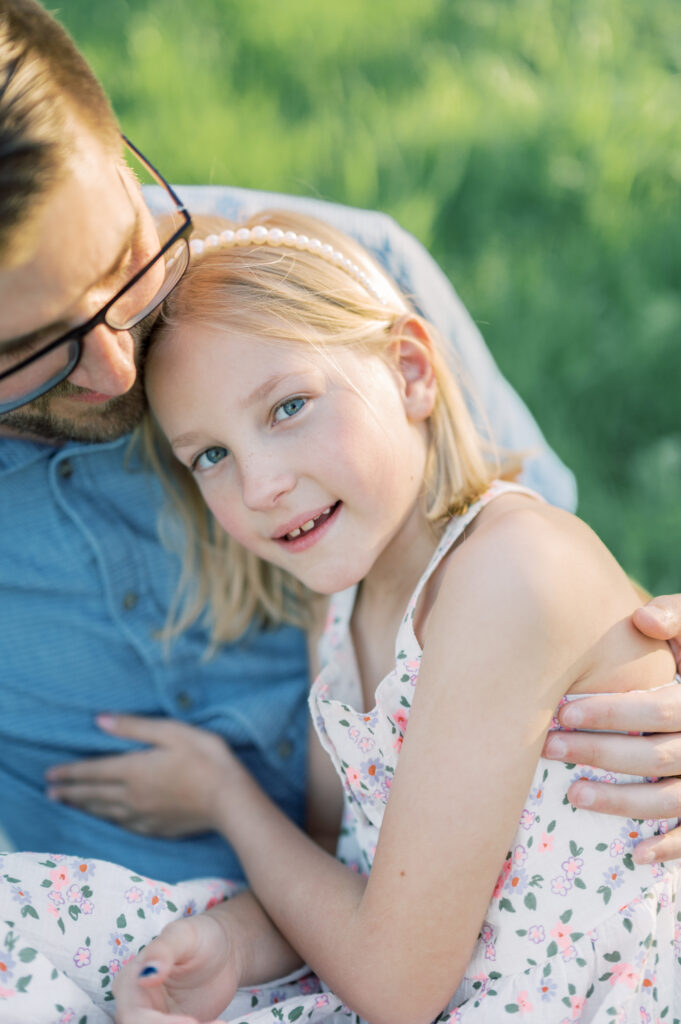 father and daughter sit together in a field