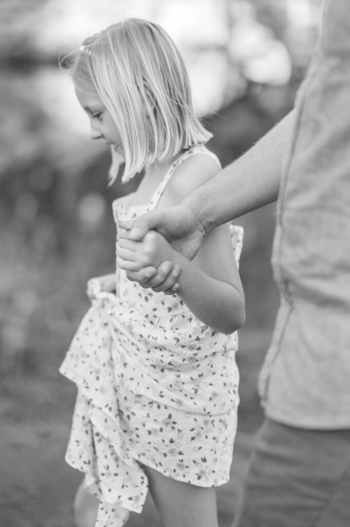 dad and daughter holds hands while walking