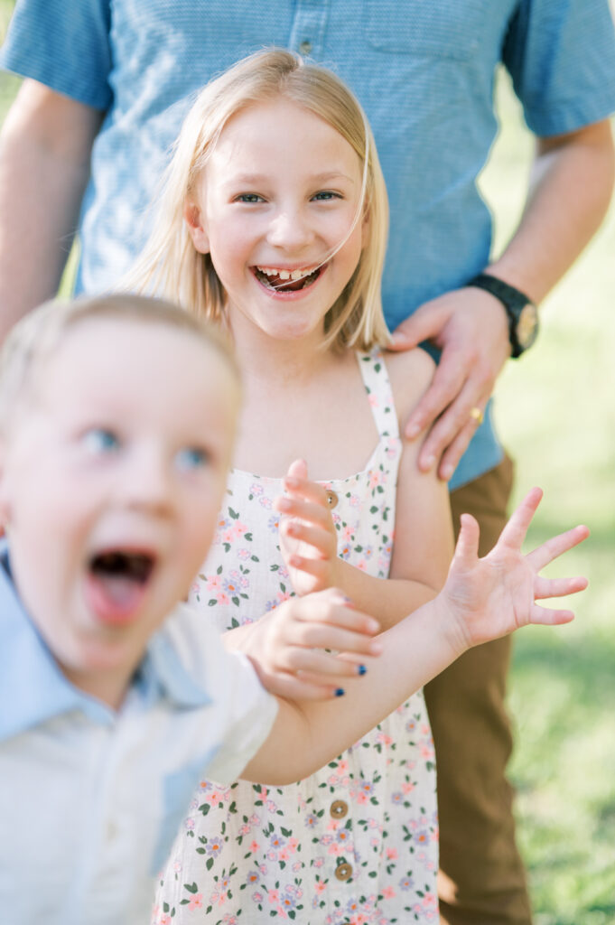 boy makes silly face during a family photo and sister laughs