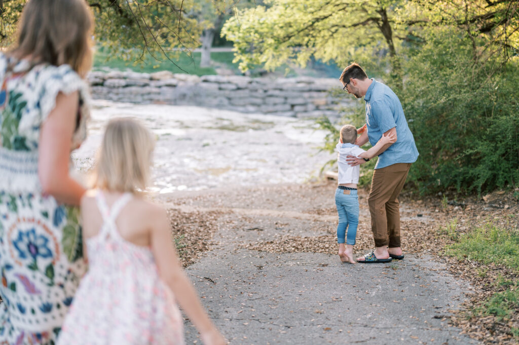 dad lifts up son while mom and daughter walk towards them
