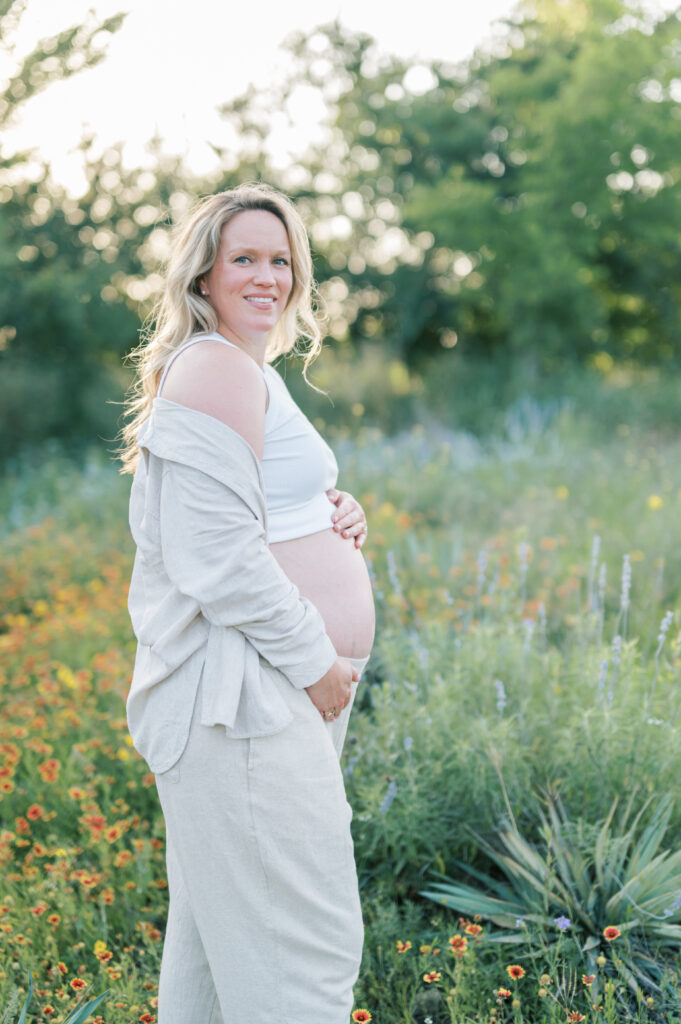 mom embraces bump in a field of wildflowers in Fort Worth