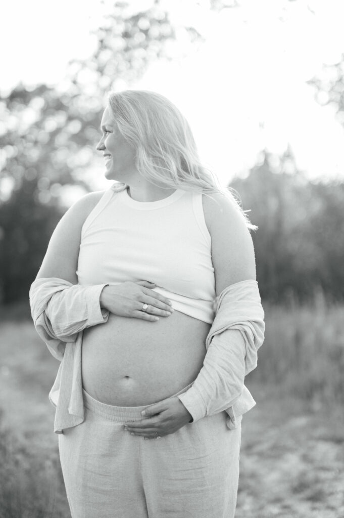 expecting mom embraces bump while looking to the side
