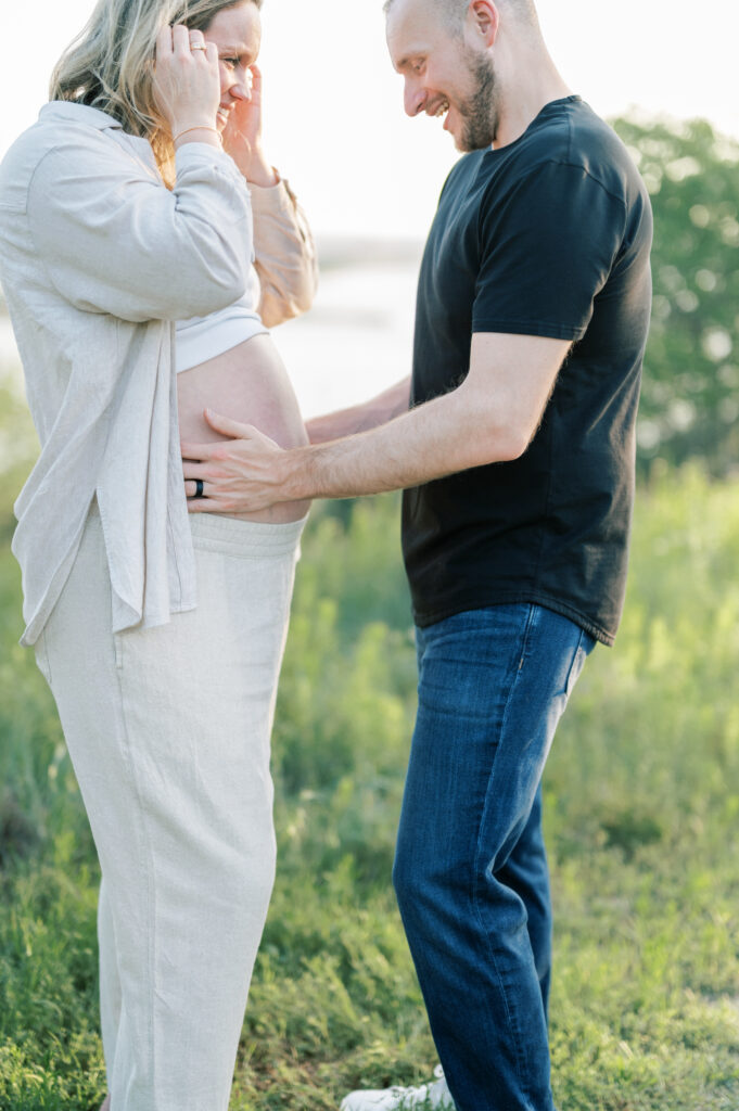 expecting dad embraces wife's bump and smiles 
