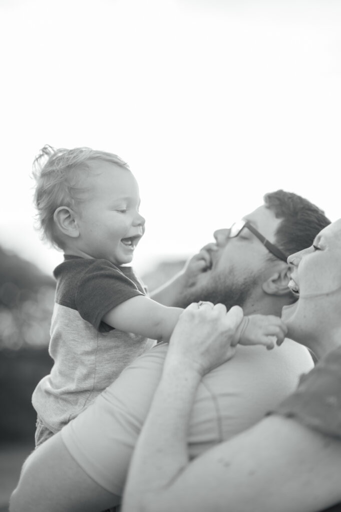 toddler boy plays with mom and dad while everyone smiles