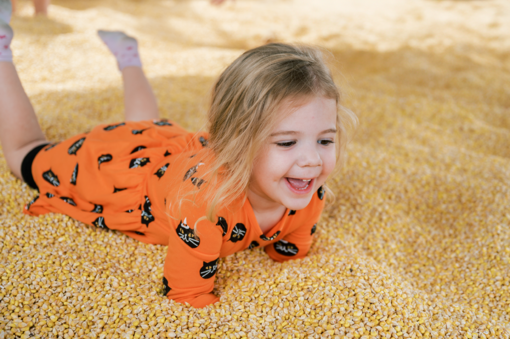 girl plays in corn during fall festival
