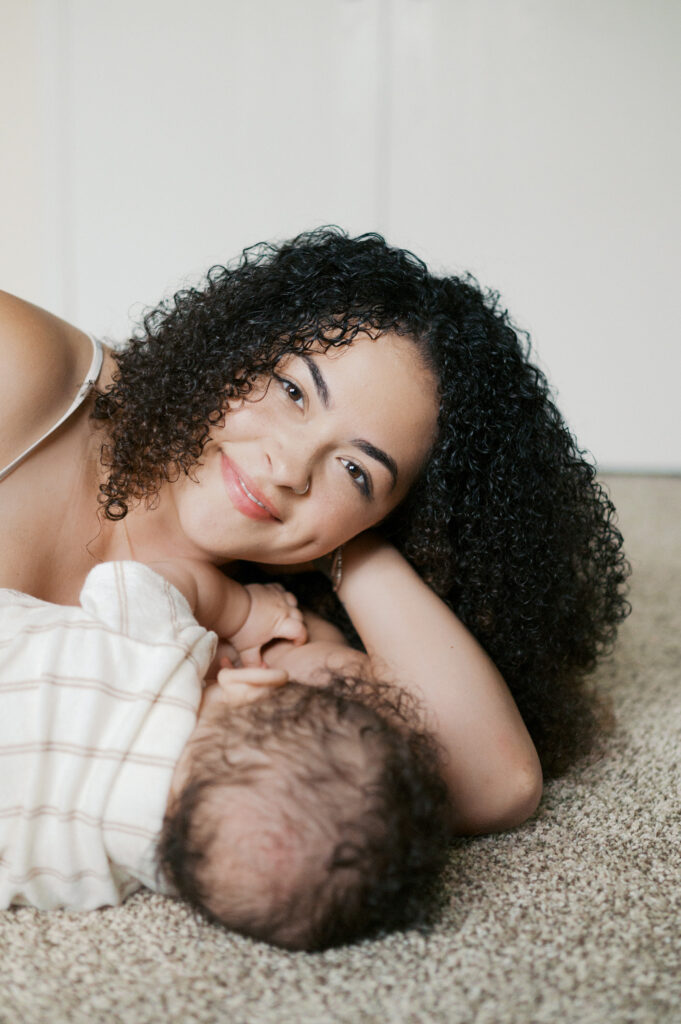 mom looks straight while laying on floor with baby boy