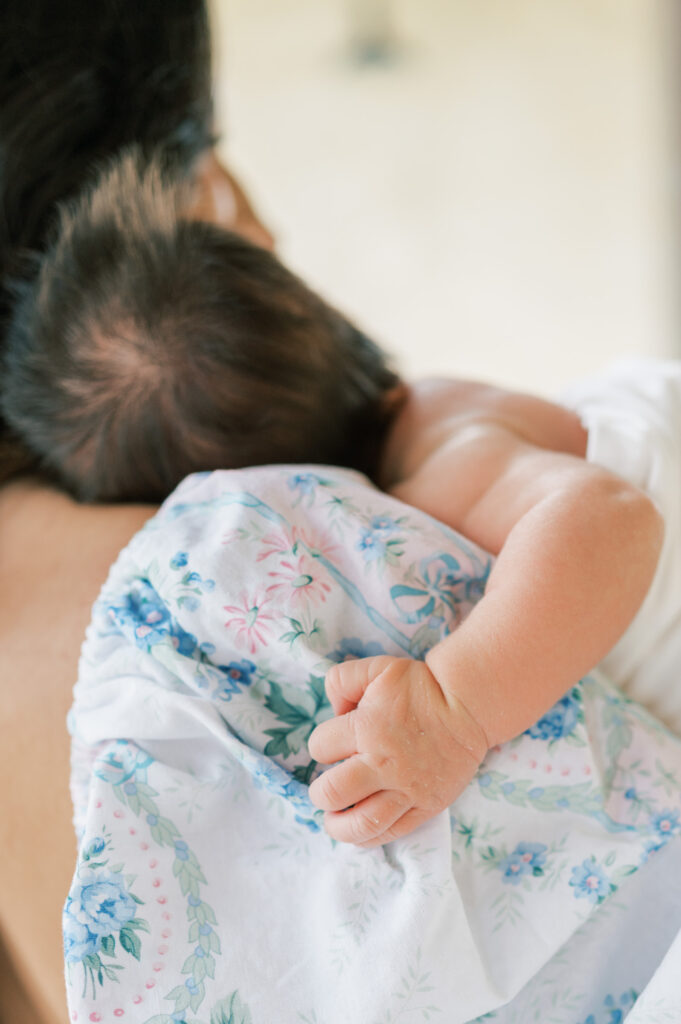 newborn baby clings to mom's dress while resting on her chest