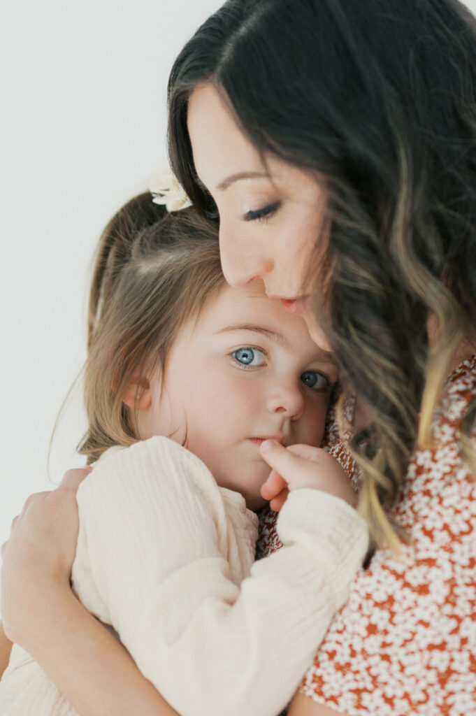 mom snuggles daughter during family photos
