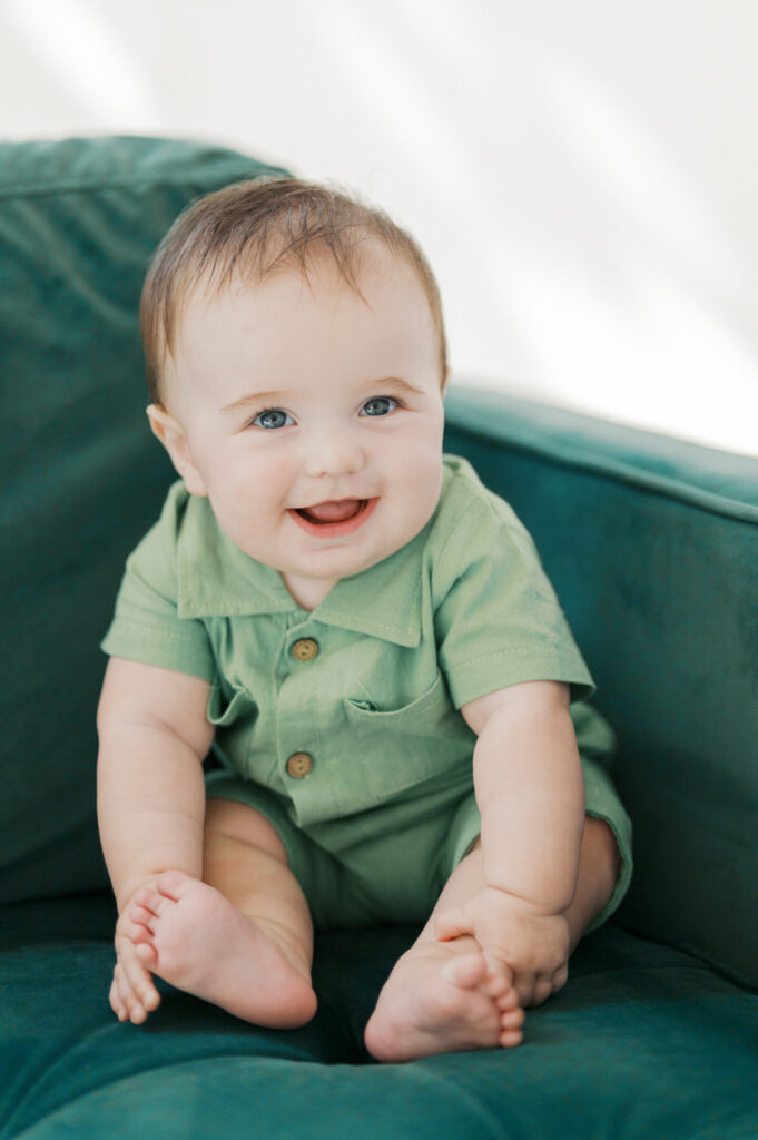 little boy smiles while sitting on green couch