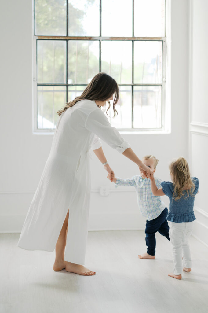 mom holds hands of twins in studio in fort worth 