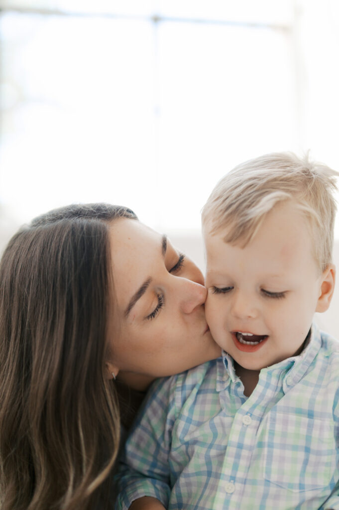 mom kisses son on cheek while he smiles