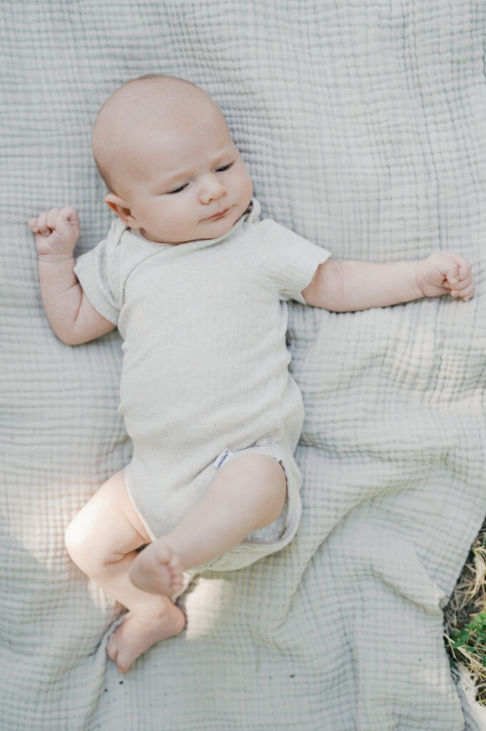 baby lays on blanket outside for photos