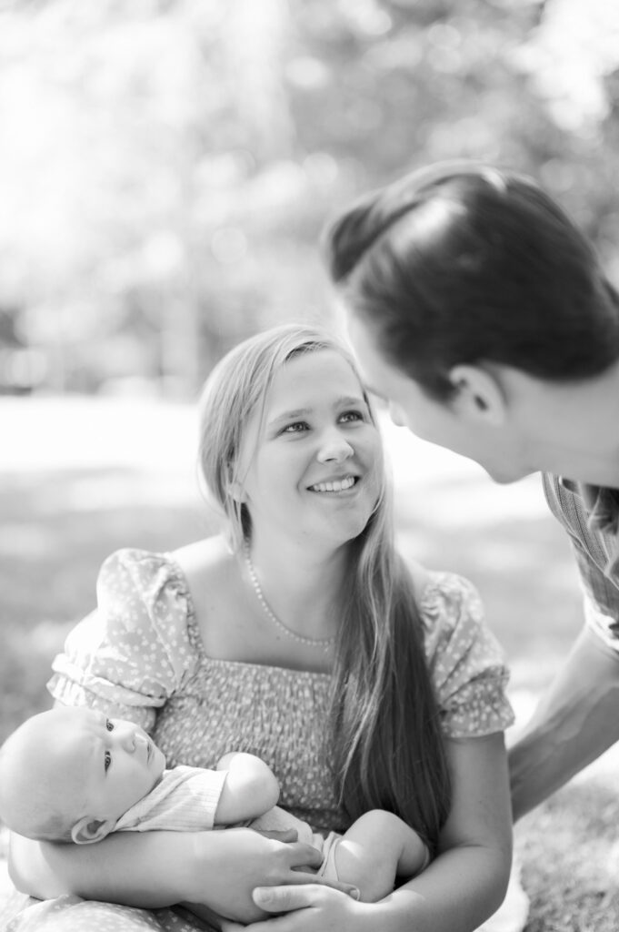 new mom looks adoringly at husband while holding newborn baby