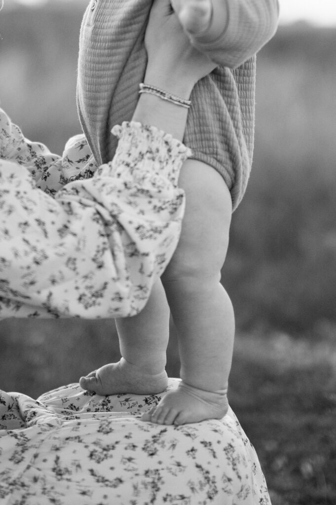 little boy stands on mom's knees