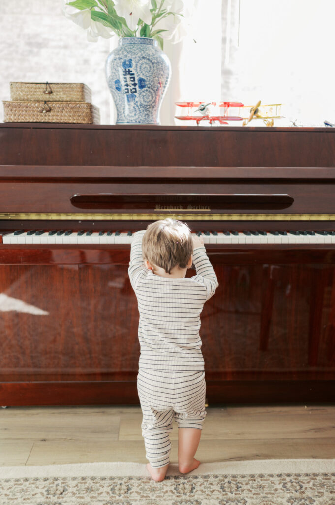 little boy plays at family piano during family photos in fort worth