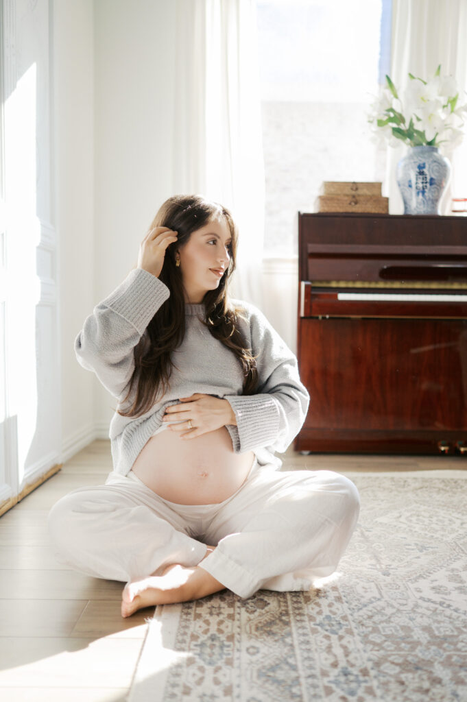 mom moves aside hair while holding baby bump