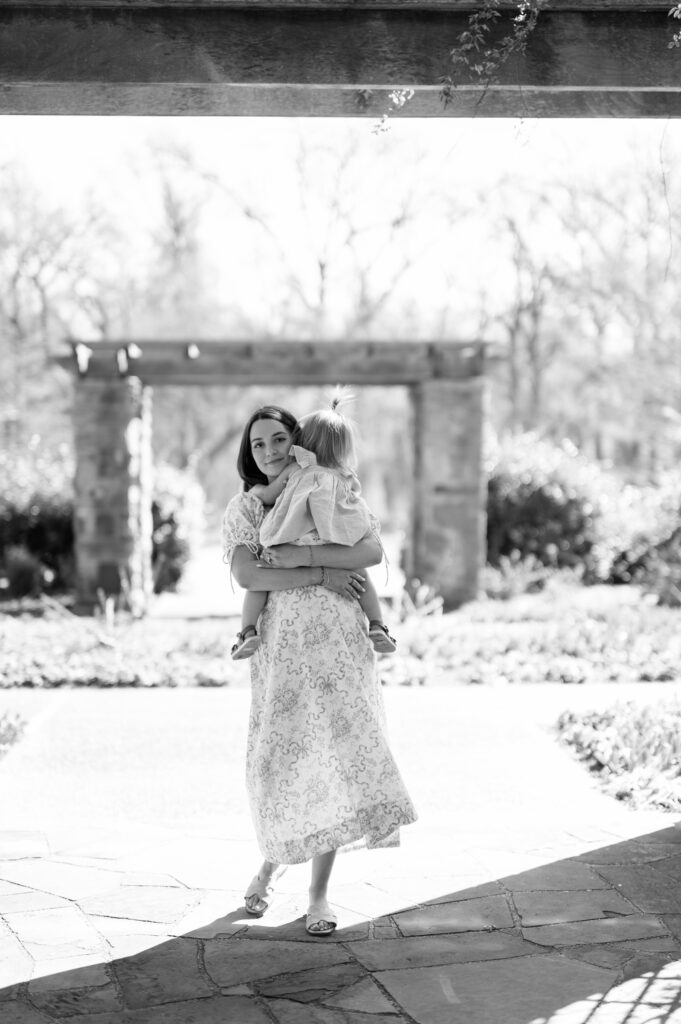 expecting mom carries toddler girl in the Fort Worth botanic garden