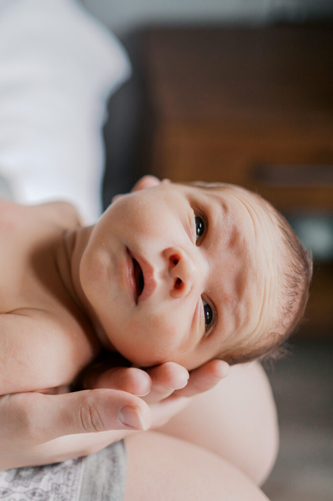 newborn baby looks out towards window during at home newborn photos