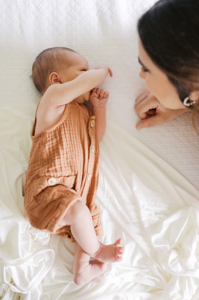 mom looks at newborn baby boy on bed