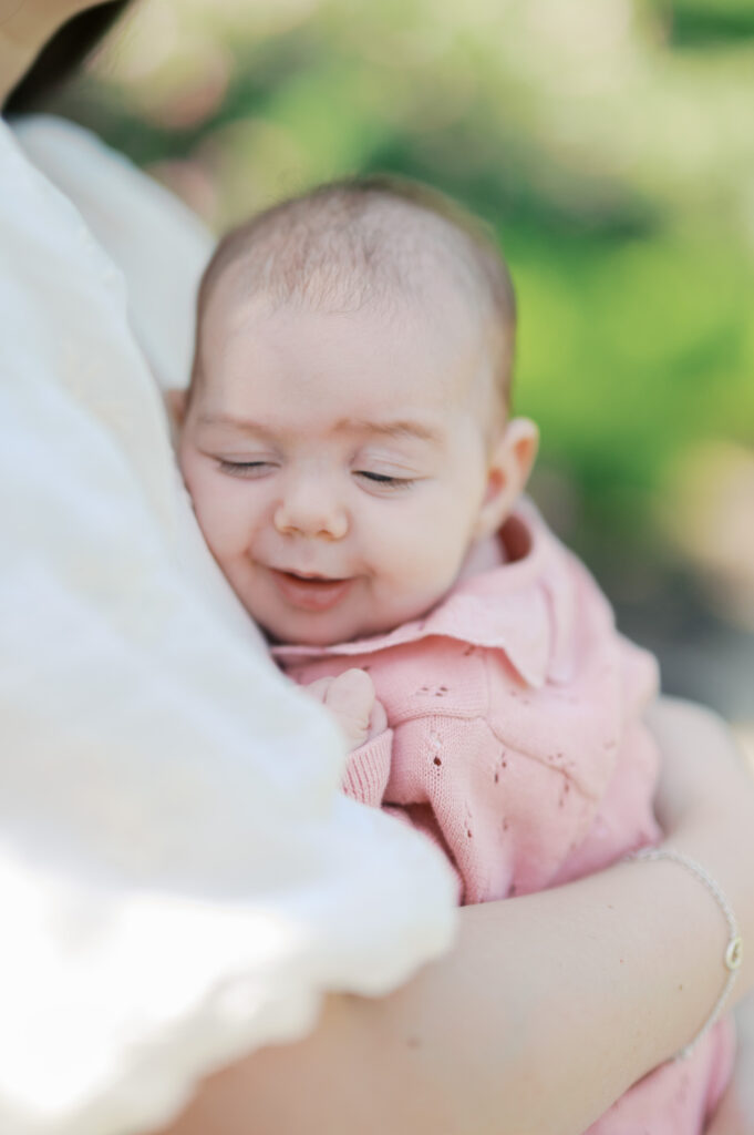 baby smiles while laying in mom's arms