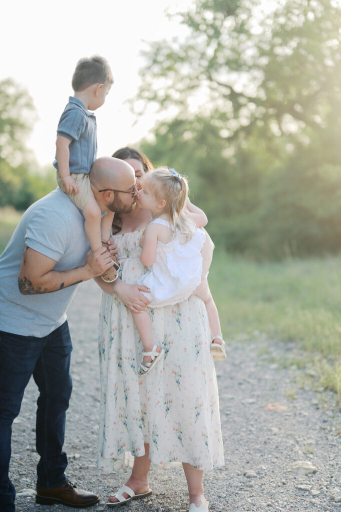 family gathers close outdoors for maternity photos
