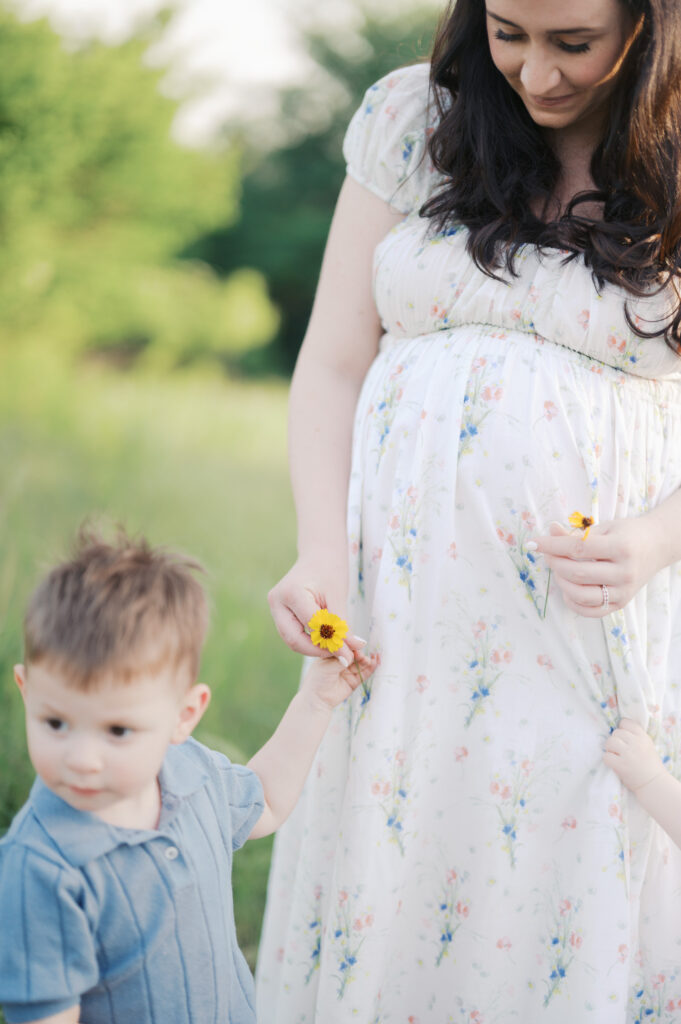 toddler boy gives mom a yellow flower during outdoor photos in fort worth