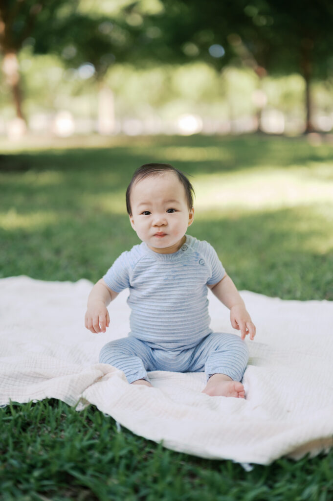 little boy looks straight while sitting on blanket outside