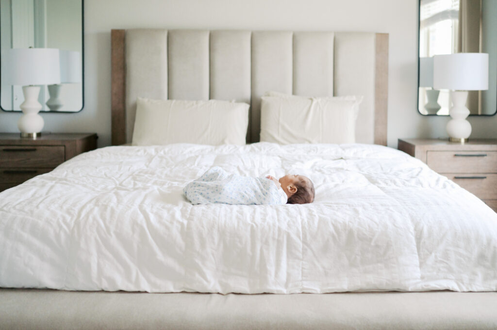 newborn baby lays on bed during newborn photos
