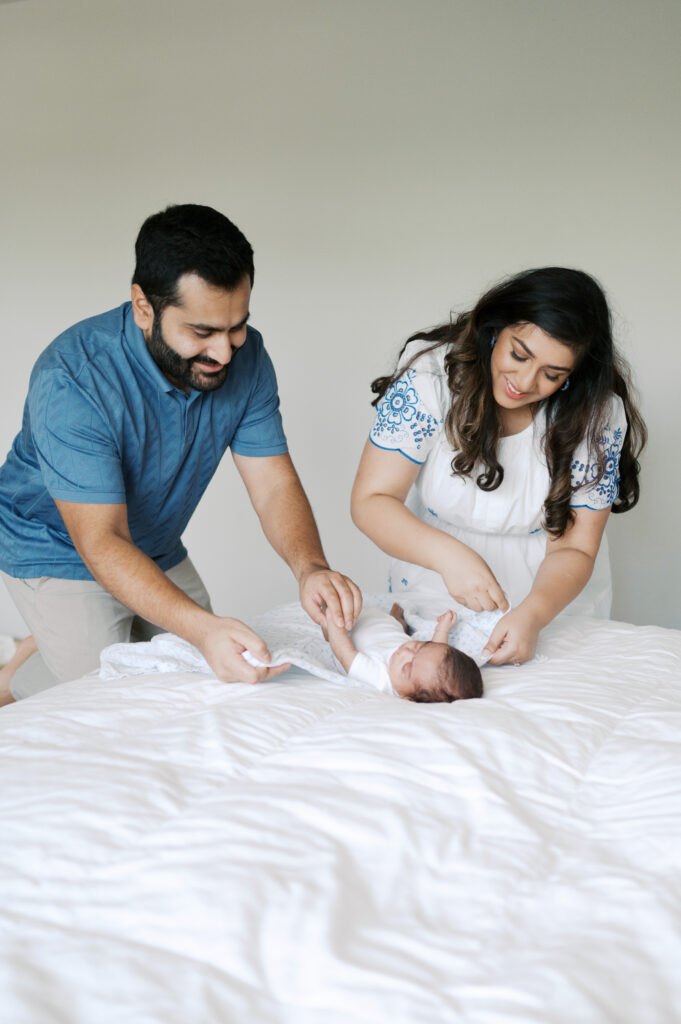 mom and dad swaddle baby during newborn photos in north fort worth