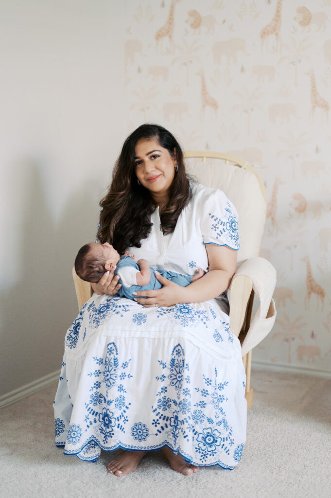 in-home newborn photos, mom sits with baby in nursery