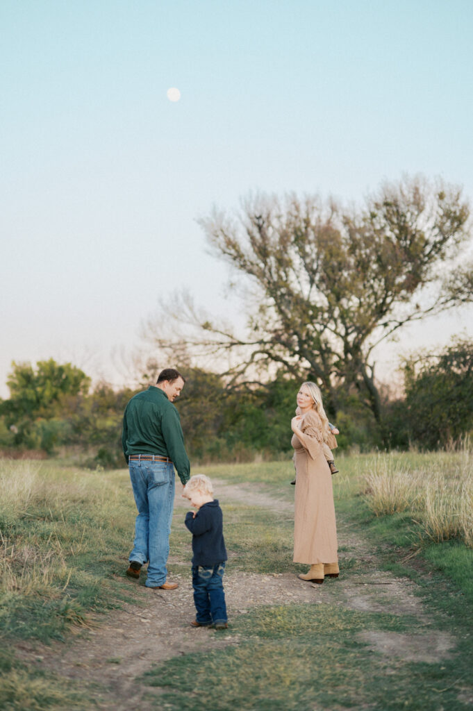 family of four walks and looks back at camera under the bright moon