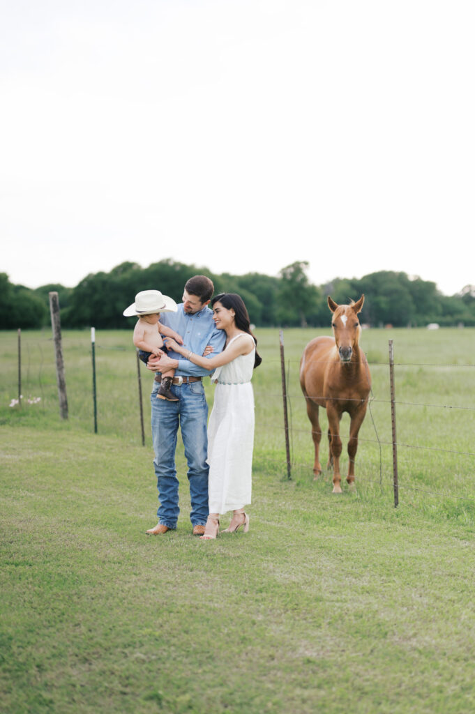 family gathers close while a horse looks ahead