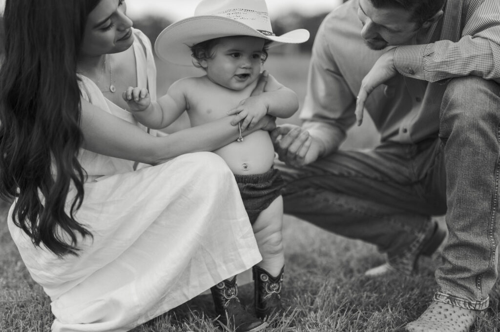 family adoringly looks at one year old during milestone photoshoot in benbrook
