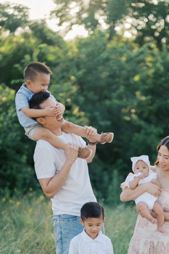 boy plays while sitting on dad's shoulders 