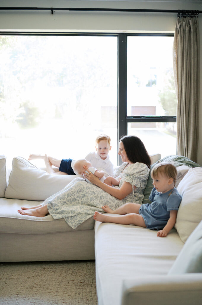 mom and three kids including newborn snuggle around the couch together