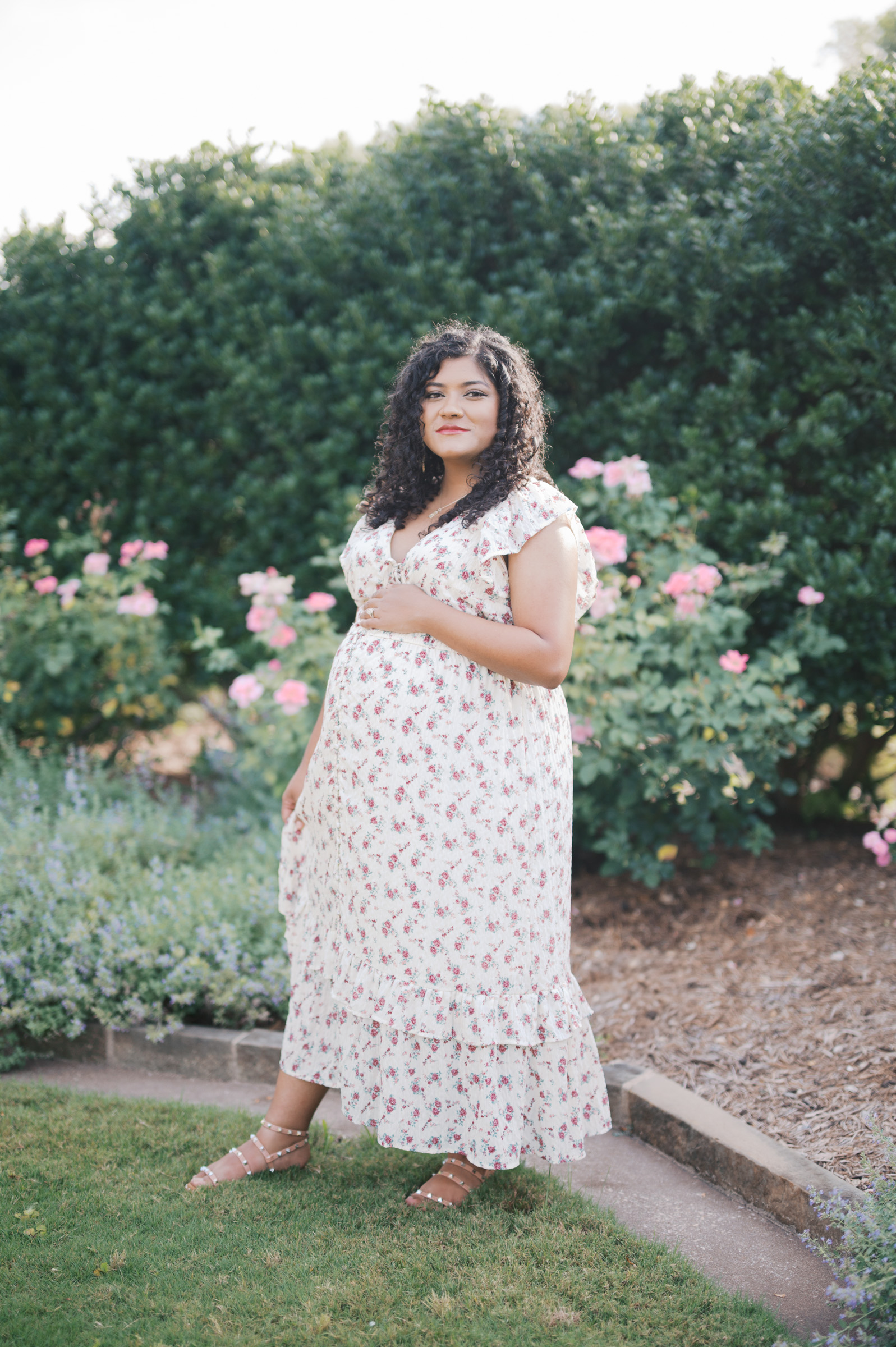 mom looks at camera during maternity photography session at the rose garden in the fort worth botanic garden